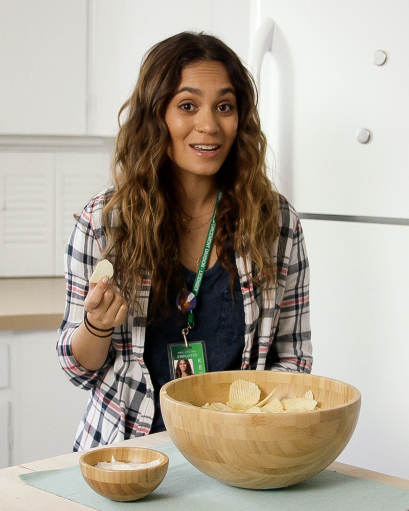 A woman with a bowl of chips and a smaller bowl of dip.